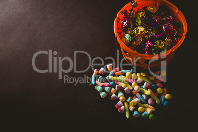 Candies by bucket with wrapped chocolate over black background