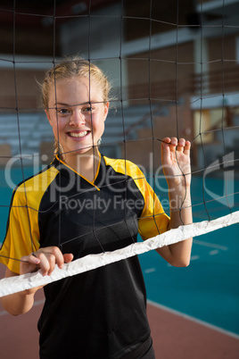 Smiling volleyball female players standing behind the net