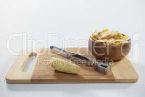 High angle view of peeler and fresh ginger with bowl on wooden cutting board