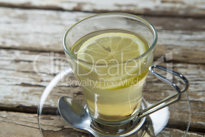 Close up of fresh ginger tea with lemon slice on weathered table