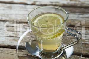 Close up of fresh ginger tea with lemon slice on weathered table