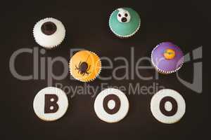 High angle view cookies with boo text by cup cakes