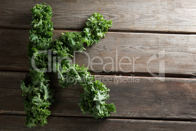 Letter K made with kale leaves on wooden table