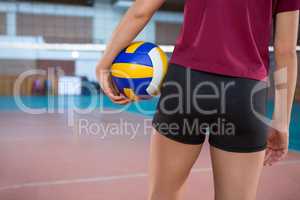 Female player holding volleyball in the court