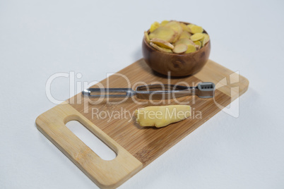 High angle view of fresh finger with peeler and bowl on wooden serving board