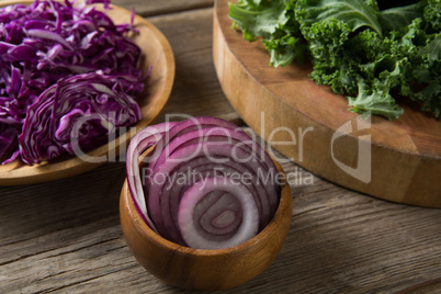 Fresh kale leaves with red cabbage and onion on wooden table