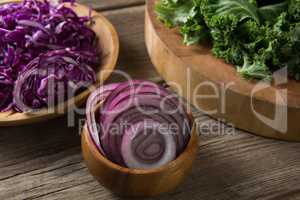 Fresh kale leaves with red cabbage and onion on wooden table