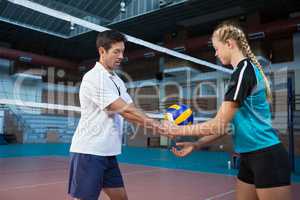 Male coach assisting volleyball player