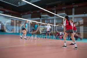 Female players playing volleyball in the court