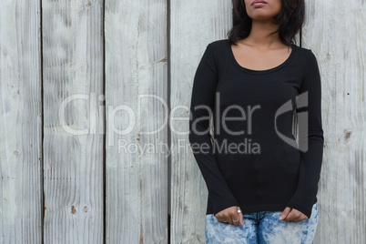 Young woman leaning on wooden wall