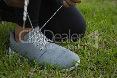 Female athlete tying shoelace on field