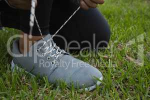 Female athlete tying shoelace on field