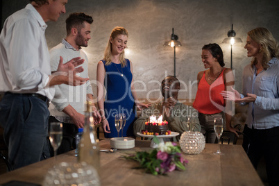 Man receiving surprise birthday cake from her friends