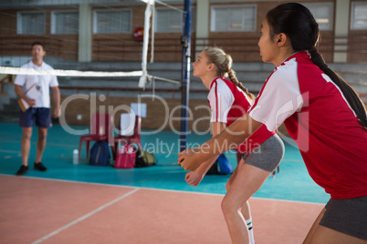 Female players playing volleyball in the court