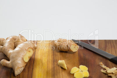 Close up of fresh chopped ginger and knife on wooden cutting board