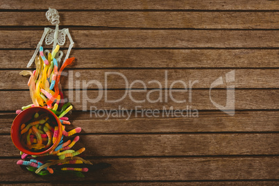 Overhead view of skeleton decoration with candies on wooden table