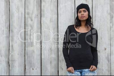 Confident woman standing against wooden wall