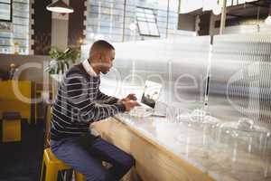 Young male customer typing on laptop while sitting at counter