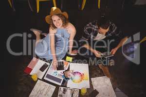 High angle portrait of smiling young female designer sitting by male colleague with sheets