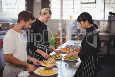 Young wait staff with fresh food in plates on kitchen counter