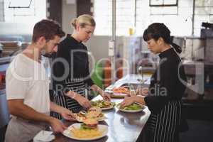 Young wait staff with fresh food in plates on kitchen counter