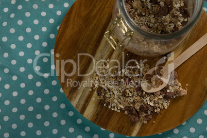 Glass jar of homemade granola and muesli with spoon on wooden board