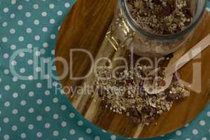 Glass jar of homemade granola and muesli with spoon on wooden board