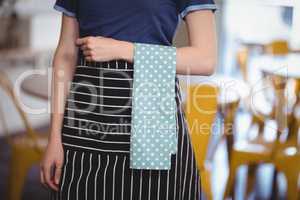Midsection of young waitress with turquoise napkin at coffee shop
