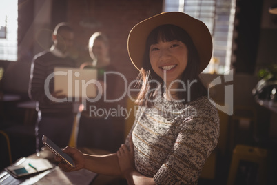 Portrait of smiling woman using smartphone against colleauges
