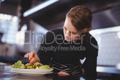 Beautiful young waitress preparing salad at counter