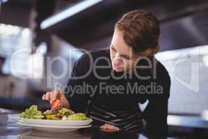 Beautiful young waitress preparing salad at counter
