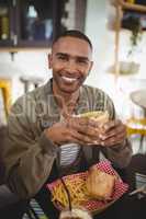 Portrait of smiling young man eating fresh sandwich at coffee shop
