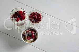 Three cups of yogurt with raspberries and pomegranate seeds