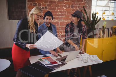 Young creative team discussing over papers at coffee shop