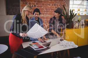 Young creative team discussing over papers at coffee shop