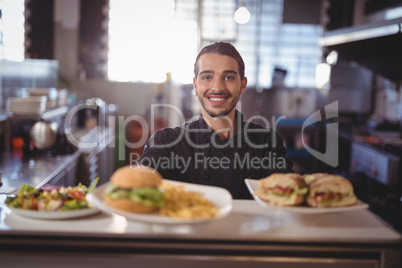 Portrait of smiling waiter serving fresh food at counter