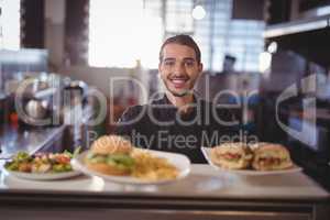 Portrait of smiling waiter serving fresh food at counter