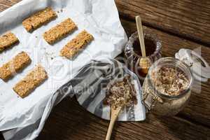 Granola bar and honey on wooden table