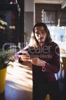 Portrait of young man with long hair using smartphone