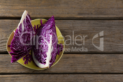 Sliced and chopped red cabbage in plate on wooden table