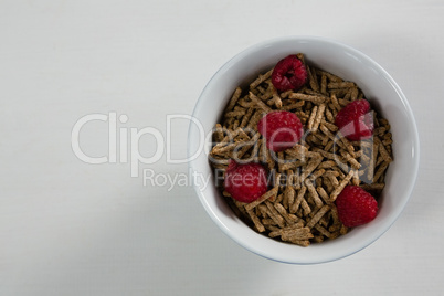 Bowl of cereal bran stick and raspberries