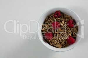 Bowl of cereal bran stick and raspberries