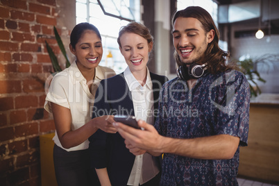 Young man showing smartphone to female friends at coffee shop