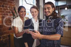 Young man showing smartphone to female friends at coffee shop