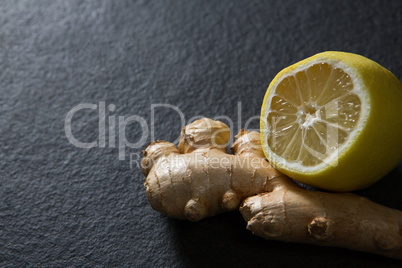 Ginger and halved lemon on black background