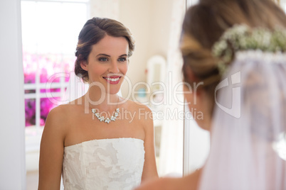 Beautiful bride looking into mirror in room