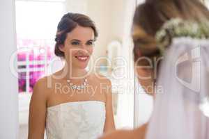 Beautiful bride looking into mirror in room