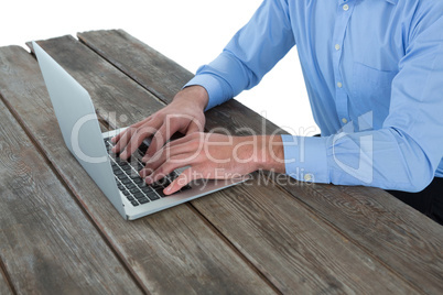 Mid section of businessman using laptop at wooden table