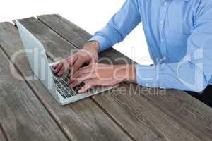 Mid section of businessman using laptop at wooden table