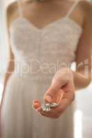 Midsection of bride holding necklace at home